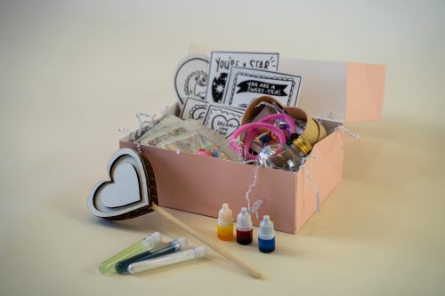 Miss Jasmine Tea's Valentine's Kit: Includes cards, a heart-shaped ornament, colorful test tubes, decorative items, and ribbons in an open gift box on a neutral background.